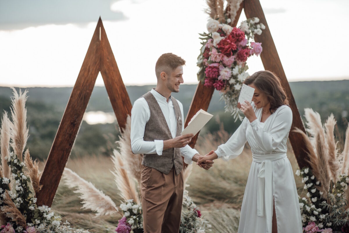 молодожены читают стихи на летней свадьбе в поле
