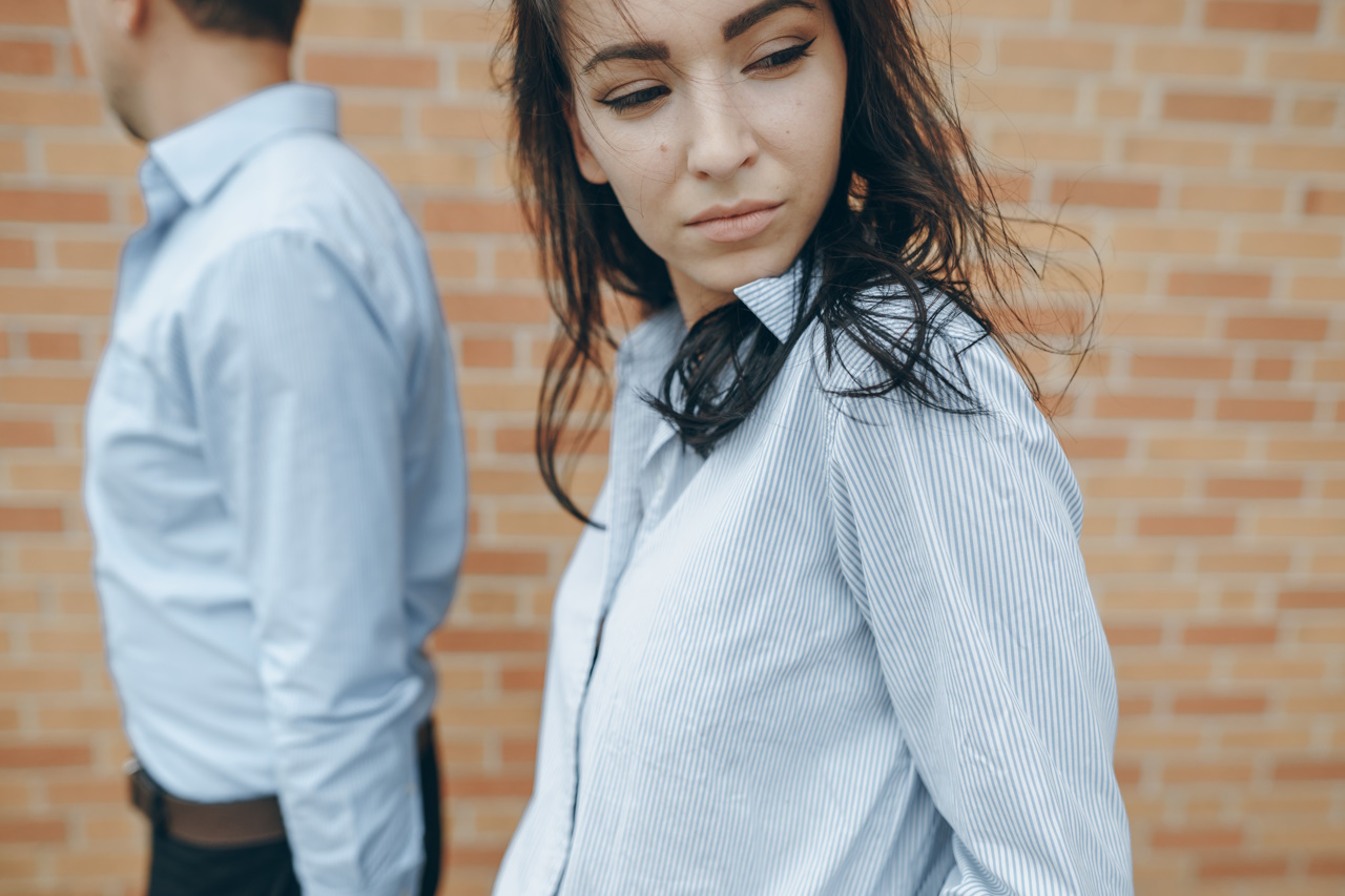 молодая красивая пара муж в рубашке и женщина в платье позируют возле стены